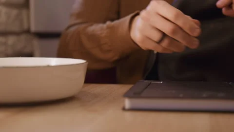 Close up of hands reaching for black notebook on wooden table with soft indoor Stock Footage 344869382