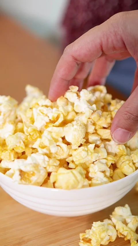 Close Up of Hands Reaching Into a White Bowl of Popcorn Stock Footage 335854841