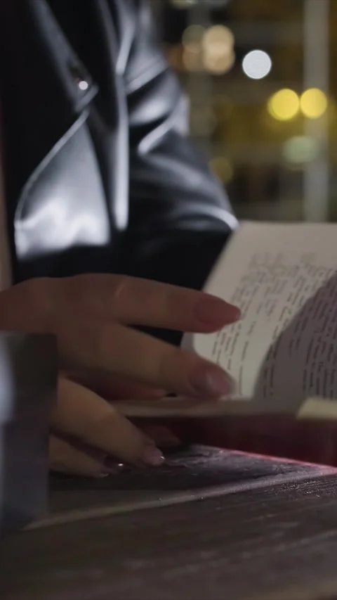 Close up hands reading red notebook on wooden table with yellow bokeh background Stock Footage 346237344