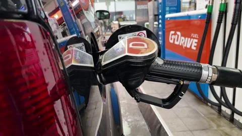 Close-up of hands refueling a car at a gas station, fuel nozzle inserted into Stock Footage 341960508