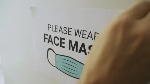 Close up - hands remove a paper sign with text: Please wear face mask Stock Footage 158501365