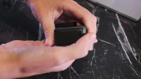 Close-up of hands removing a battery from an action camera slot, demonstrating Stock Footage 333649388