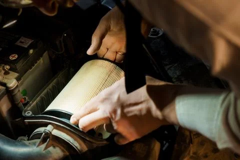 Close-Up of Hands Replacing Car Air Filter Under Hood in Automotive Maintenan Foto stock