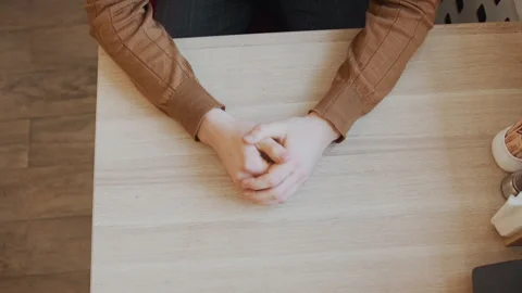 Close up of hands resting on wooden tabletop with condiments and napkins in soft 스톡 동영상 344874482
