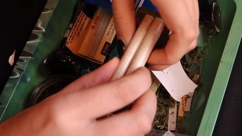 Close up of hands rolling a joint using a roller machine. Stock Footage 118938362
