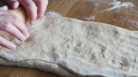 Close-up of hands rolling out dough with a wooden rolling pin. Stock Footage 331851651