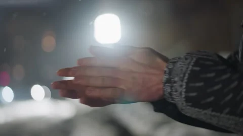 Close Up of Hands Rubbing Together During Cold Night with Blurred Light Stock Footage 316453907
