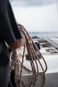 Close up of hands of a sailor man coiling up a rope, the halyard on a sailboat Stock Photos