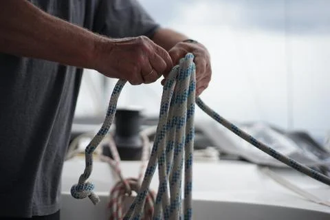 Close up of hands of a sailor man coiling up a rope, the halyard on a sailboat5 Stock Photos
