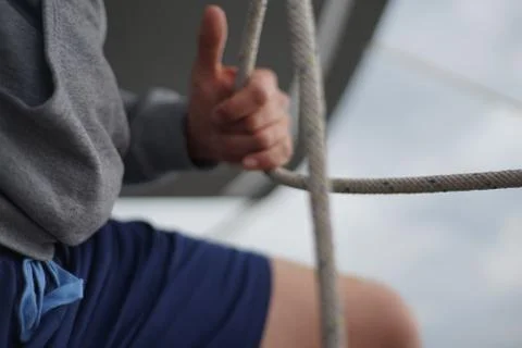 Close up of hands of a sailor man coiling up a rope, the halyard on a sailboat Stock Photos
