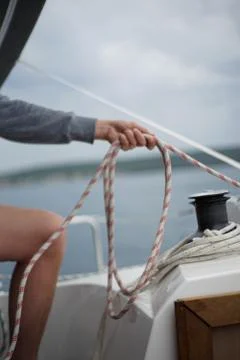 Close up of hands of a sailor man coiling up a rope, the halyard on a sailboat Stock Photos