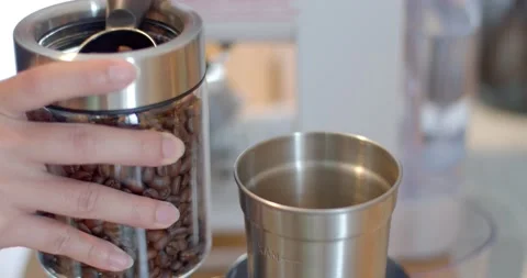 Close-up hands scoop roasted coffee with a spoon into a coffee grinder. Stock Footage 223209511