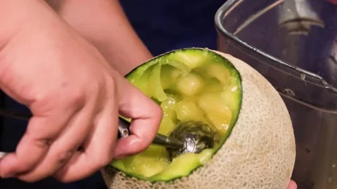 Close-Up of Hands Scooping Fresh Cantaloupe Melon with a Melon Baller Tool Stock Footage 345648259