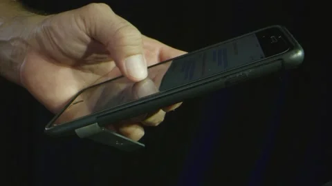 Close-up of hands scrolling over news on phone Stock Footage 130596297