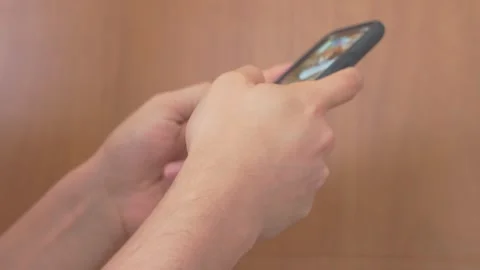 Close-Up of Hands Scrolling Social Media on Phone Against Wooden Background Stock Footage 248920076