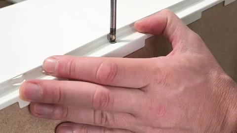 Close-up of hands securing a drawer rail with a screwdriver on a white Stock Footage 341859558