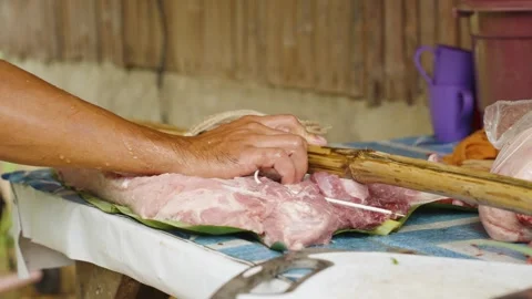 Close Up of Hands Securing Pork Belly with Bamboo Poles for Grilling Stock Footage 342030535