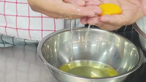 Close up of hands separating a raw yellow egg yolk from the white. 스톡 동영상 339200673