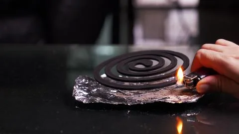Close-up, hands set fire to black spiral insect repellent mosquito, coil incense Stockfoto's
