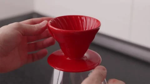 Close-up of hands setting up red V60 dripper on glass carafe Stock Footage 332720229