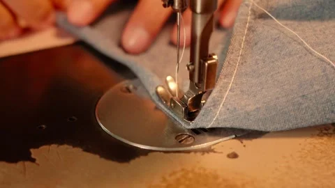 Close-Up of Hands Sewing Blue Denim Fabric with a Vintage Sewing Machine Stock Footage 341907290
