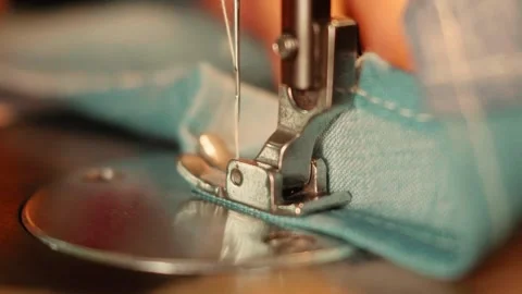 Close-Up of Hands Sewing Blue Denim Fabric with a Vintage Sewing Machine Stock Footage 341907293