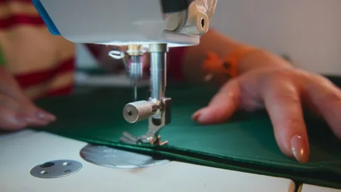 Close-up of hands sewing dark green fabric on machine Stock Footage 333750237