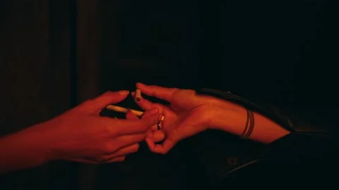 Close-up of hands sharing cigarettes in a dark, neon-lit club. Stock Footage 232907184