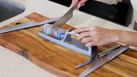 Close up of hands sharpening a kitchen knife on a multi stage sharpener on .. Vídeos de archivo 332719021