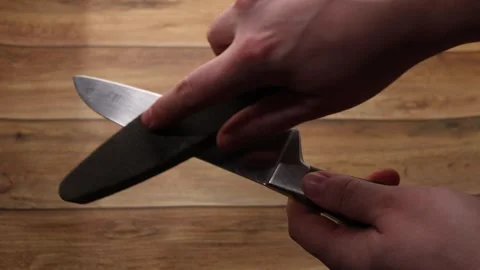 Close-up of hands sharpening a kitchen knife on a whetstone Stock Footage 339181512