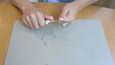 Close-up of hands sharpening a pencil with a knife. Concept of manual pencil Stock Footage 316089591