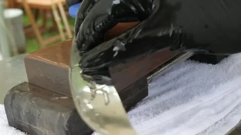 Close-up of Hands Sharpening a Professional Kitchen Knife on a Whetstone for Bar Stock Footage 338212876