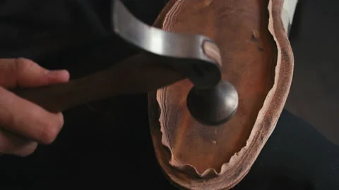 Close up hands shoemaker taps sole shoes with hammer. Workshop hipsters. Craft Stock Footage 138262119