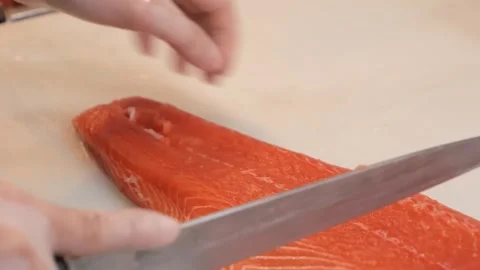 Close-up of Hands Skillfully Slicing Fresh Raw Salmon Fillet for Sushi Preparati Stock Footage 333521898