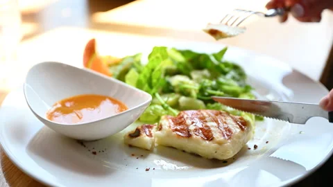 Close up of hands slicing baked cheese dish beside vegetable salad Stock Footage 346550714