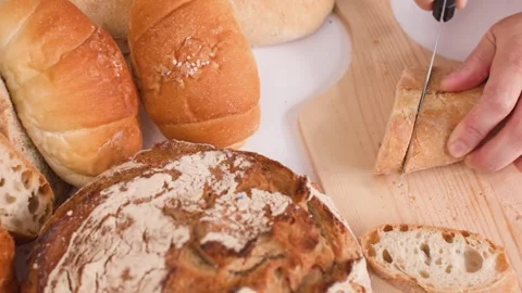 Close Up of Hands Slicing Fresh Bread on Wooden Board Stock Footage 337533316