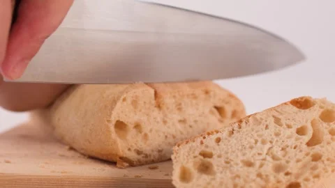 Close Up of Hands Slicing Fresh Crusty Bread on Wooden Board Stockbeeldmateriaal 337224901