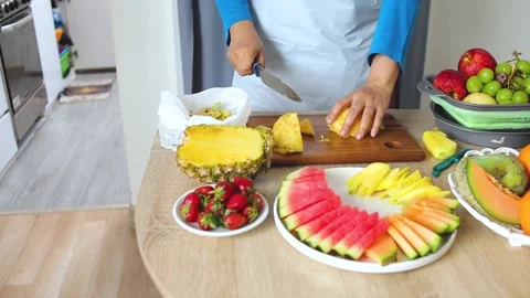 Close-up of hands Slicing fresh pineapple on wooden board with assortment of 库存影片 330972700