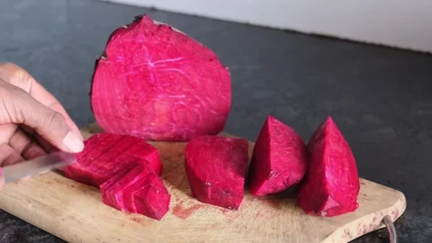 Close-up of hands slicing fresh red beetroot on a wooden cutting board Stock-Footage 329975660