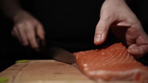 Close-Up of Hands Slicing Fresh Salmon Fillet on a Dark Background Stock Footage 291526730