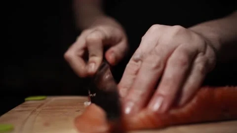 Close-Up of Hands Slicing Fresh Salmon Fillet on a Dark Background Stock Footage 291526737