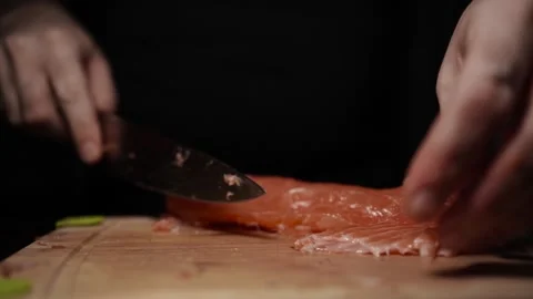 Close-Up of Hands Slicing Fresh Salmon Fillet on a Dark Background Vidéo 296232727