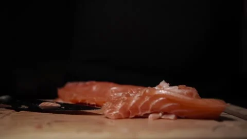Close-Up of Hands Slicing Fresh Salmon Fillet on a Dark Background Stock Footage 296233019