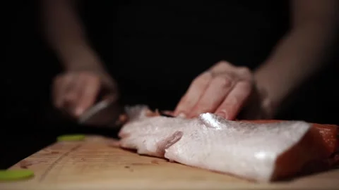 Close-Up of Hands Slicing Fresh Salmon Fillet on a Dark Background Stock Footage 296233022
