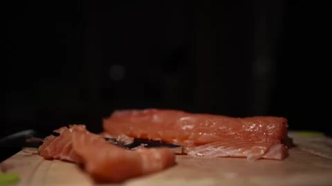 Close-Up of Hands Slicing Fresh Salmon Fillet on a Dark Background Stock Footage 296233027