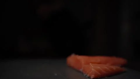 Close-Up of Hands Slicing Fresh Salmon Fillet on a Dark Background Stock Footage 296233354