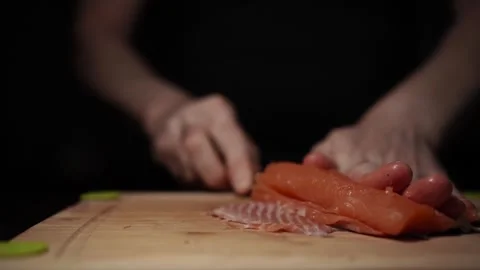 Close-Up of Hands Slicing Fresh Salmon Fillet on a Dark Background 스톡 동영상 296233355