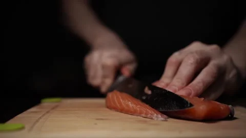 Close-Up of Hands Slicing Fresh Salmon Fillet on a Dark Background Video stock 296233356