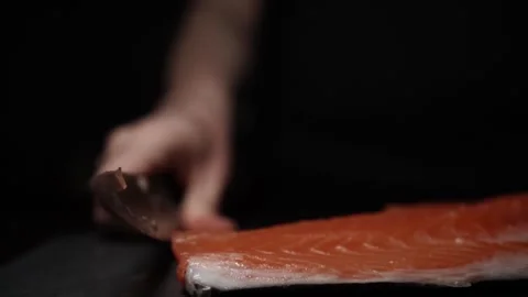 Close-Up of Hands Slicing Fresh Salmon Fillet on a Dark Background Stock Footage 296233429