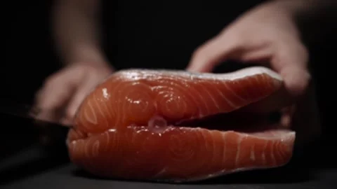 Close-Up of Hands Slicing Fresh Salmon Fillet on a Dark Background 스톡 동영상 296234403